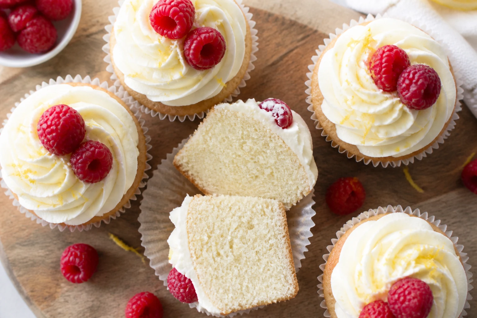 Cupcakes glacés au mascarpone avec une rosace pochée à la douille étoile, framboises et zeste de citron