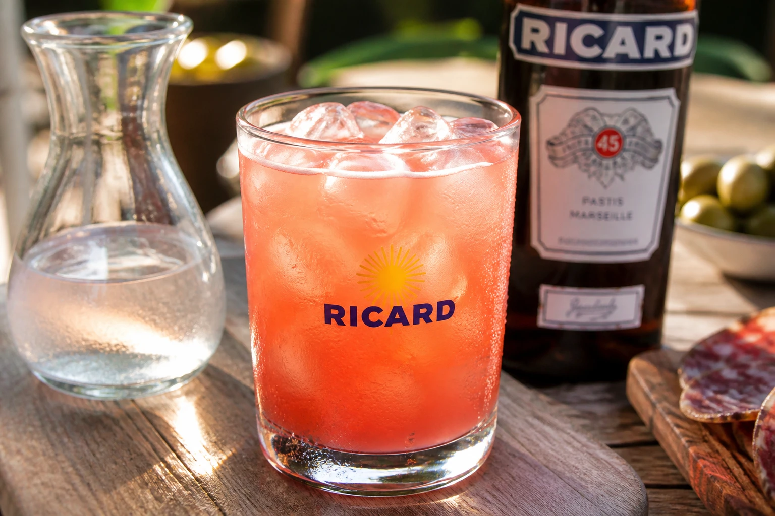 Verre de Ricard grenadine rose-orangé avec glaçons sur une table en bois